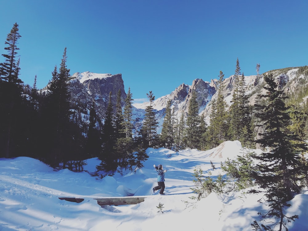 person riding on snowboard on snow covered mountain during daytime