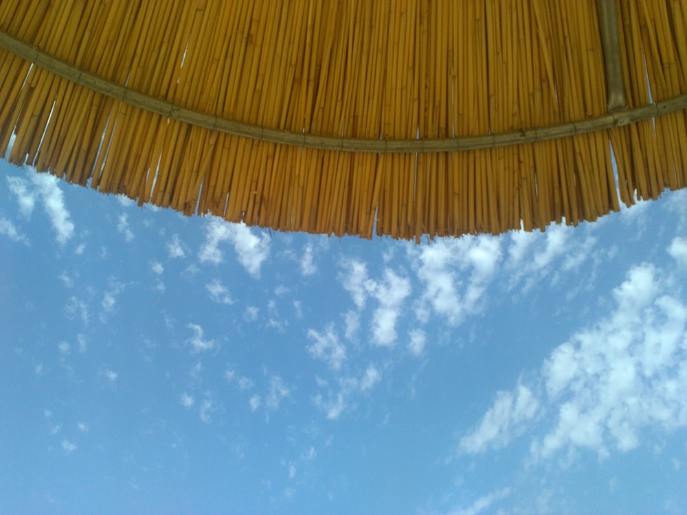 paraguas tejido marrón bajo el cielo azul y las nubes blancas durante el día