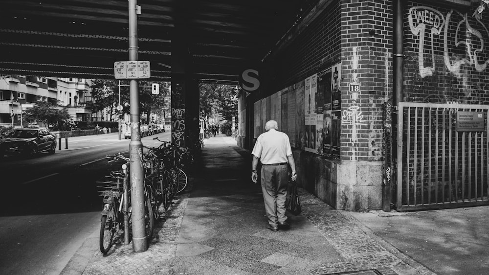 uomo in camicia bianca che cammina sul marciapiede durante il giorno