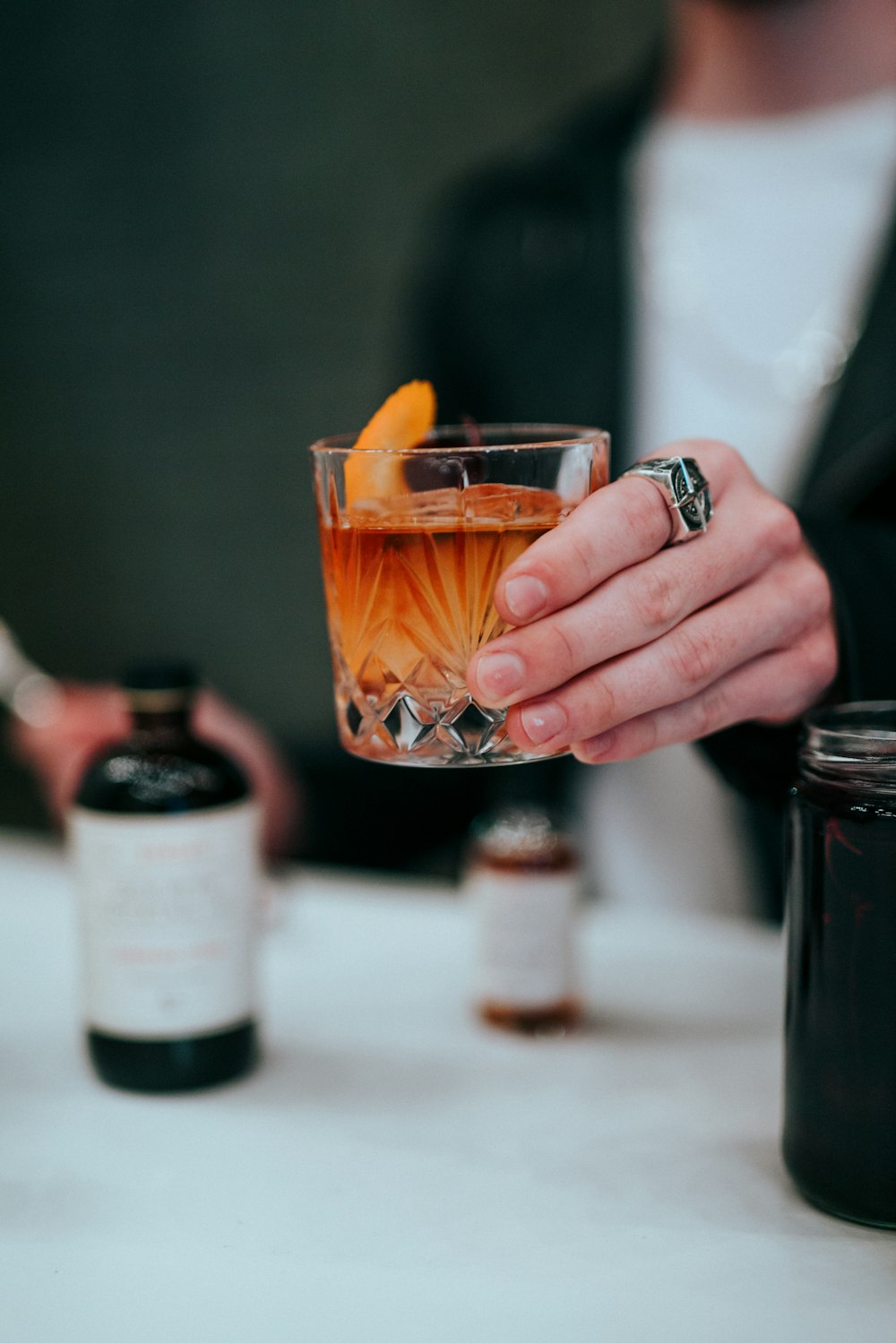 person holding clear drinking glass with orange liquid