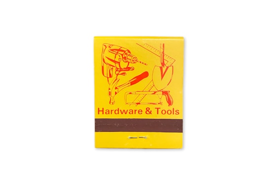 A yellow matchbook cover featuring an illustration of various tools including a drill, a trowel, and a ruler. The text 'Hardware & Tools' is printed in red at the bottom.