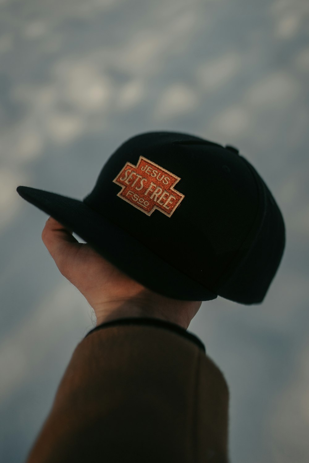 man in black and orange fitted cap