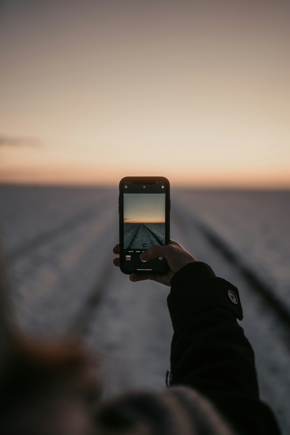 person holding iphone taking photo of sun