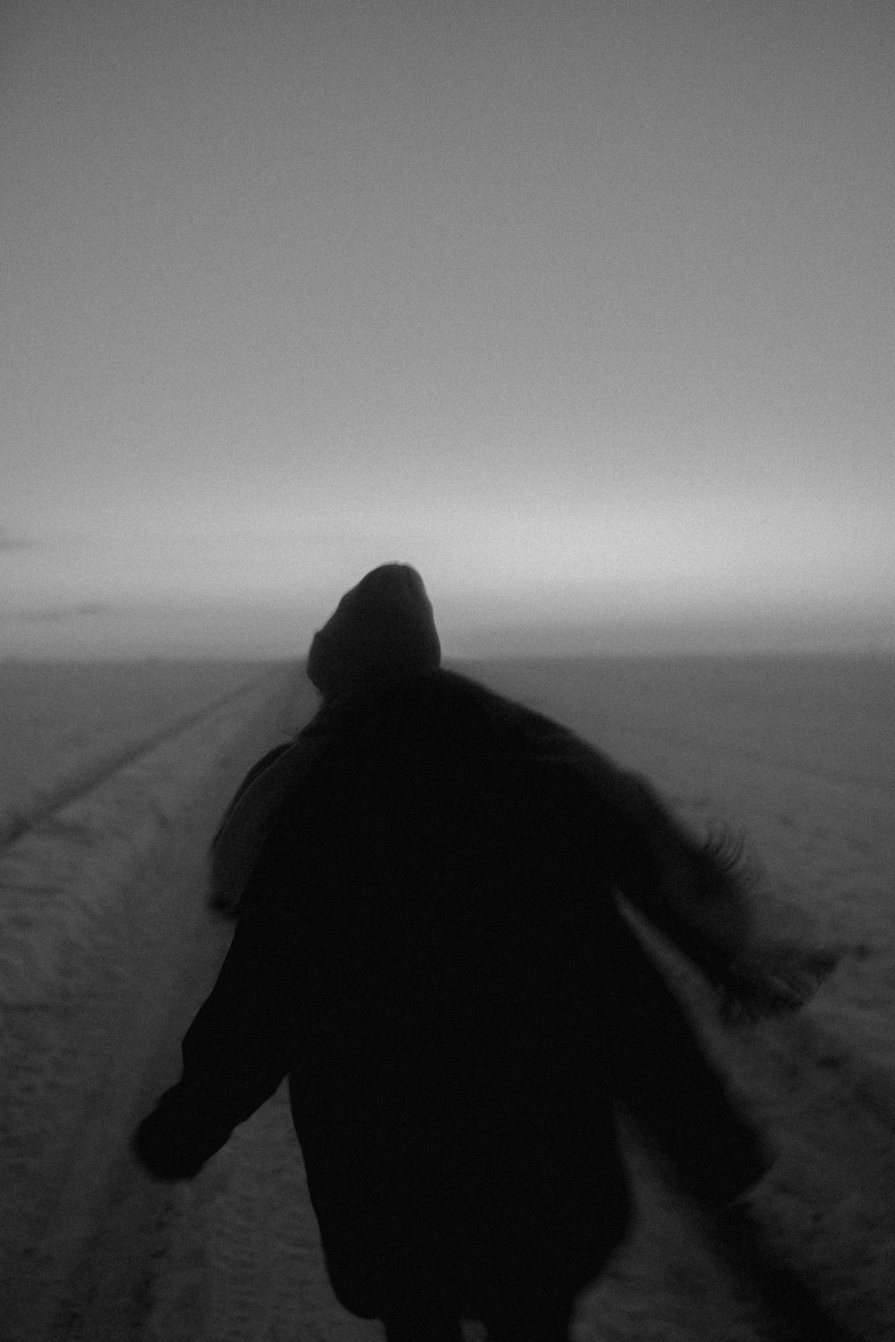 person in black coat walking on snow covered ground