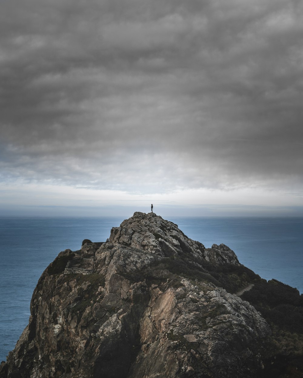 person standing on rock formation near body of water during daytime