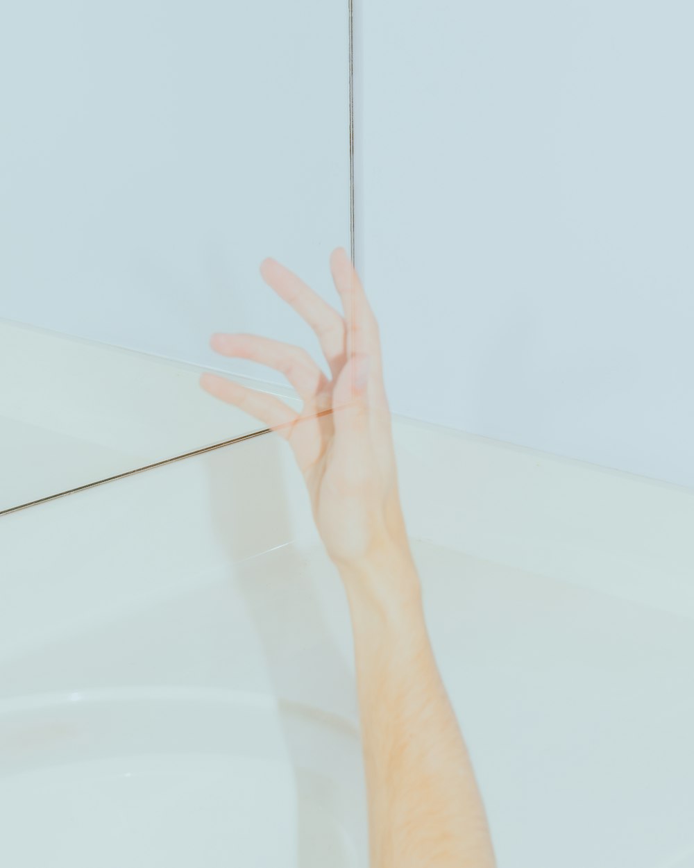 persons left hand on white bathtub