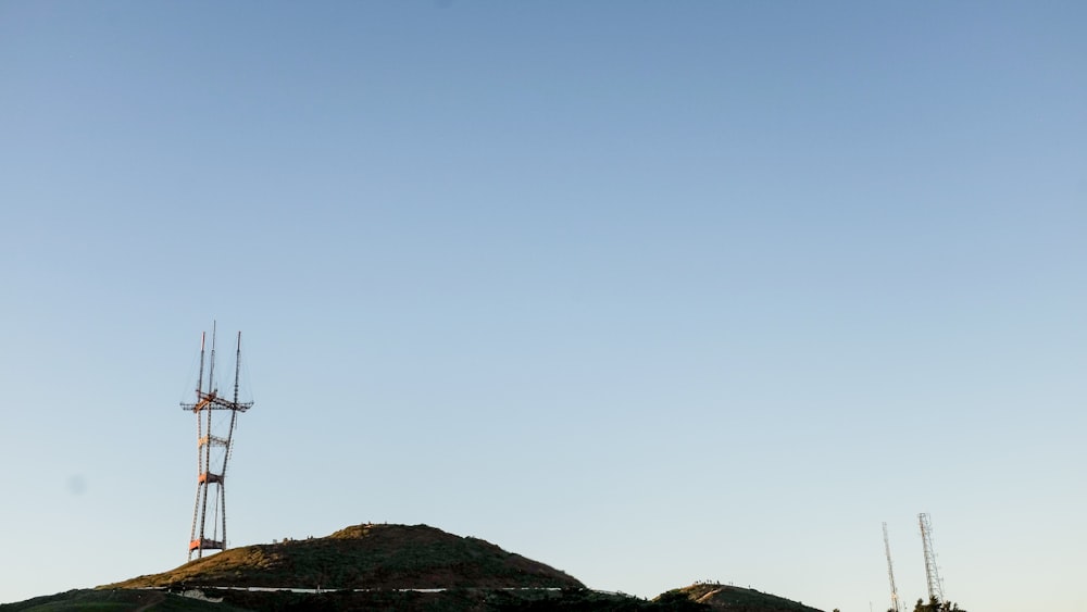 black wind mill on green grass field under blue sky during daytime