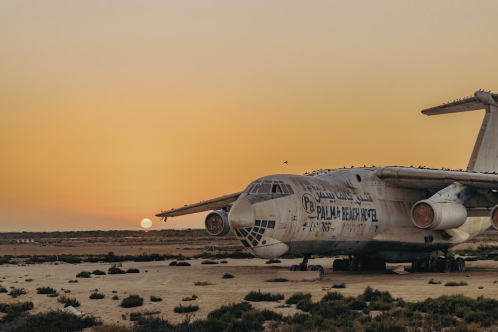 avion blanc sur un champ brun au coucher du soleil