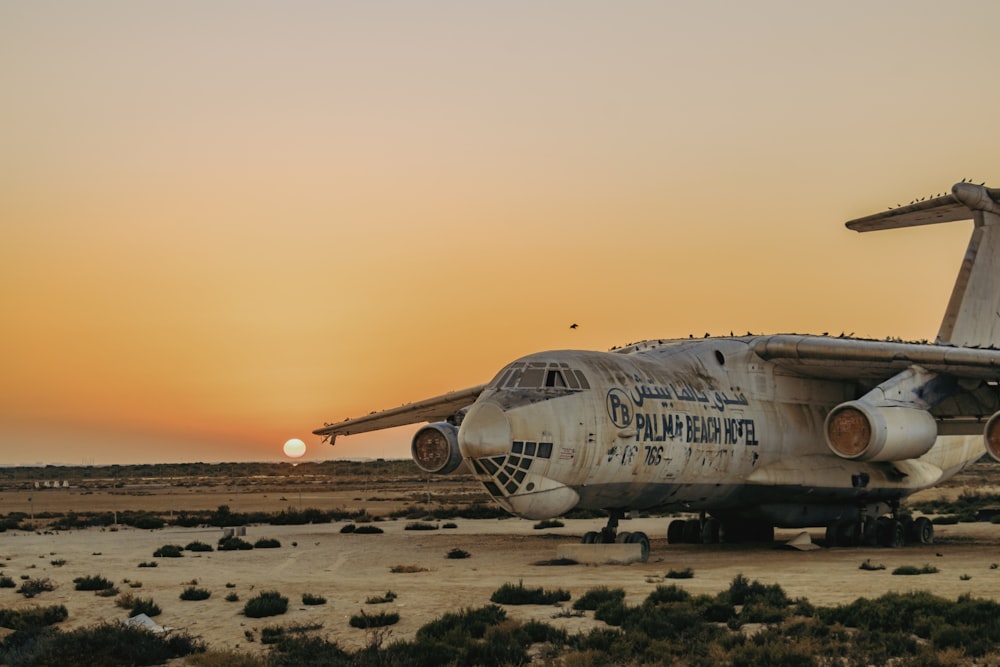white passenger plane on brown field during sunset