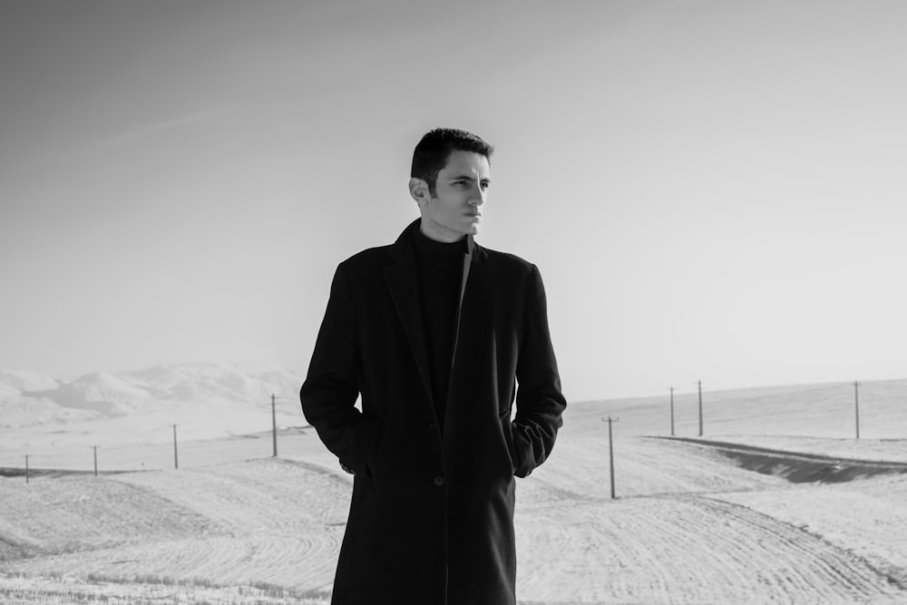 man in black coat standing on snow covered ground
