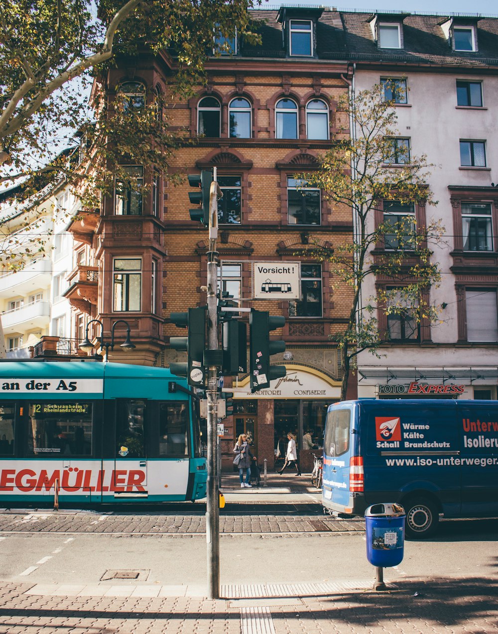 Autobus blanc et bleu sur la route près de l’immeuble brun pendant la journée