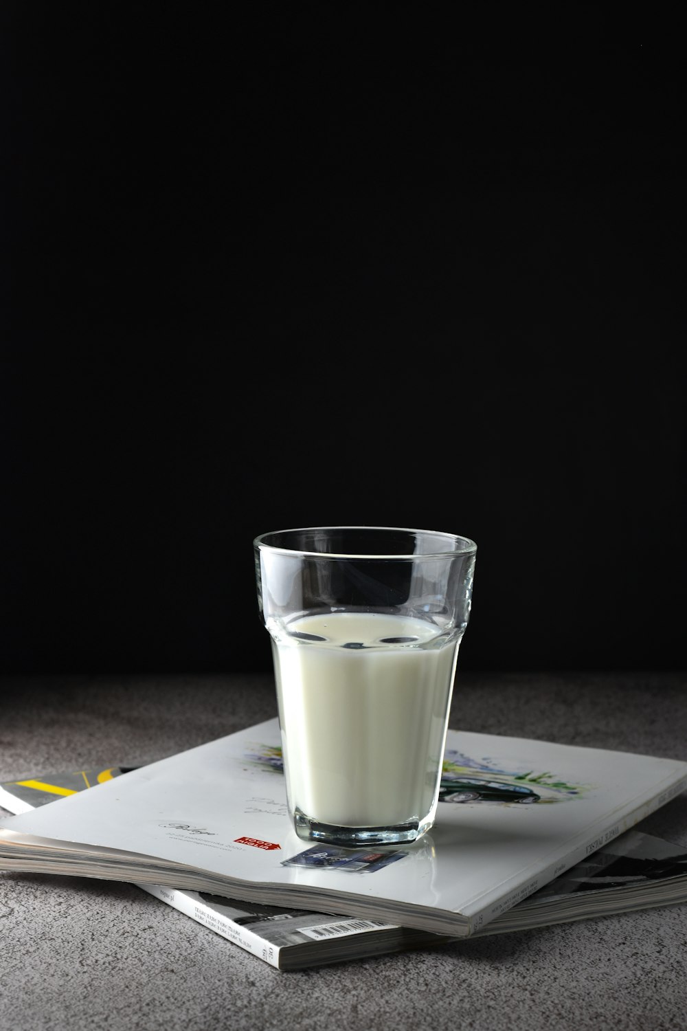 Vaso transparente con líquido blanco sobre libro blanco