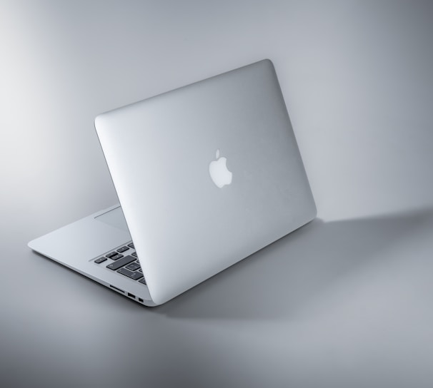 silver macbook on white table