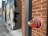 A brick wall with a red and metallic fire department connection labeled 'AUTO. SPKR. FIRE DEPT. CONNECTION' is prominently featured. The wall is adorned with colorful urban graffiti. Beside the brick wall, there is an alleyway with additional murals and street art.