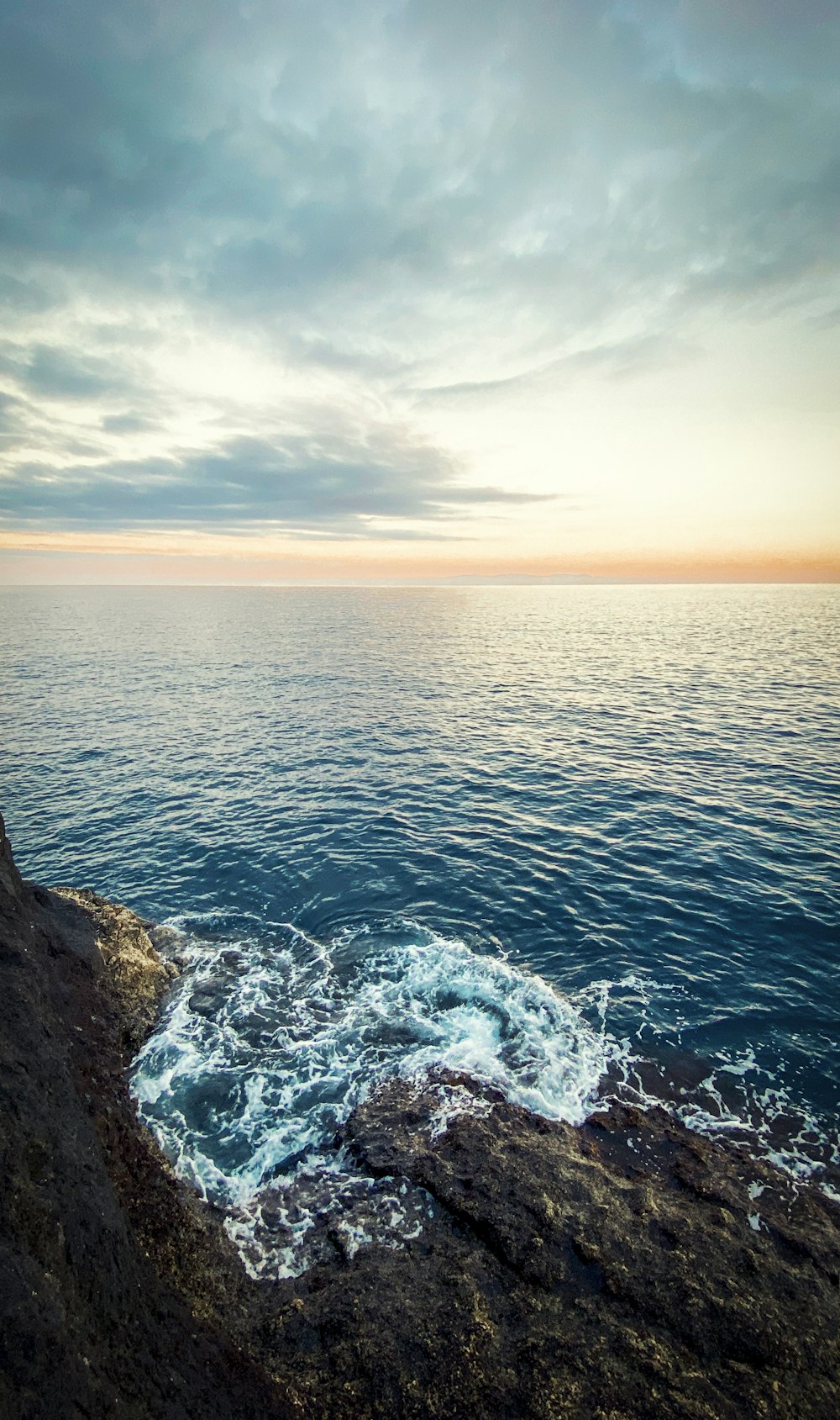 Onde dell'oceano che si infrangono sulla formazione rocciosa nera durante il giorno