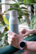 person holding white and gray bottle