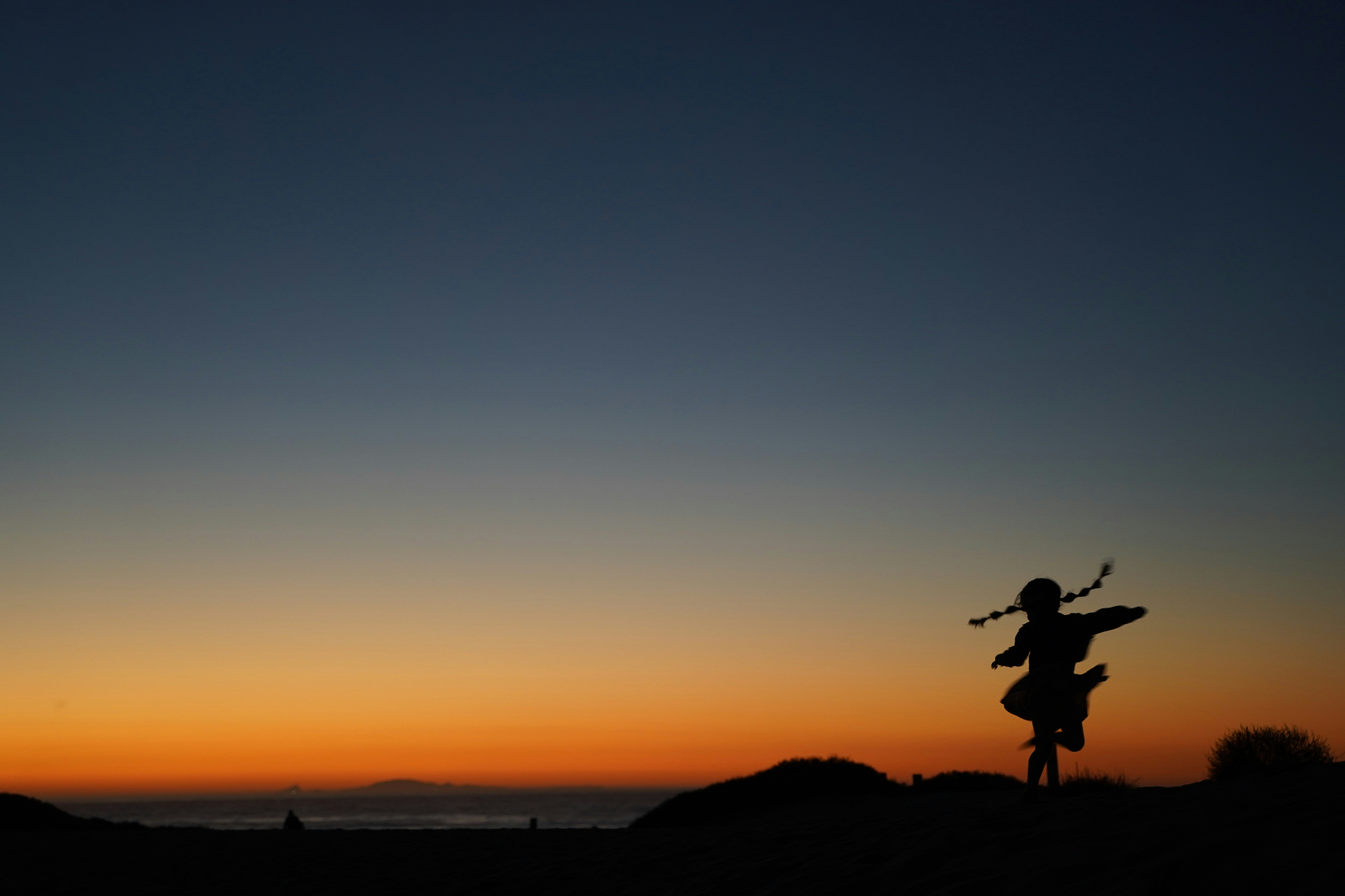 silhouette of man jumping on the beach during sunset