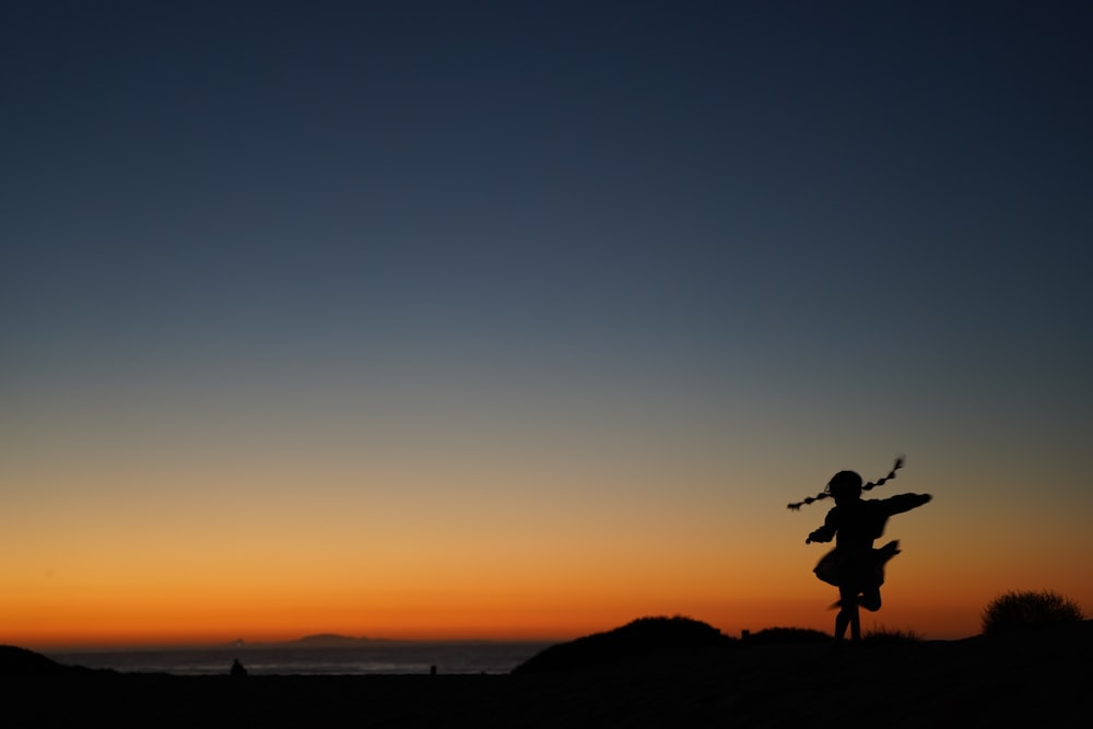 silhouette of man jumping on the beach during sunset