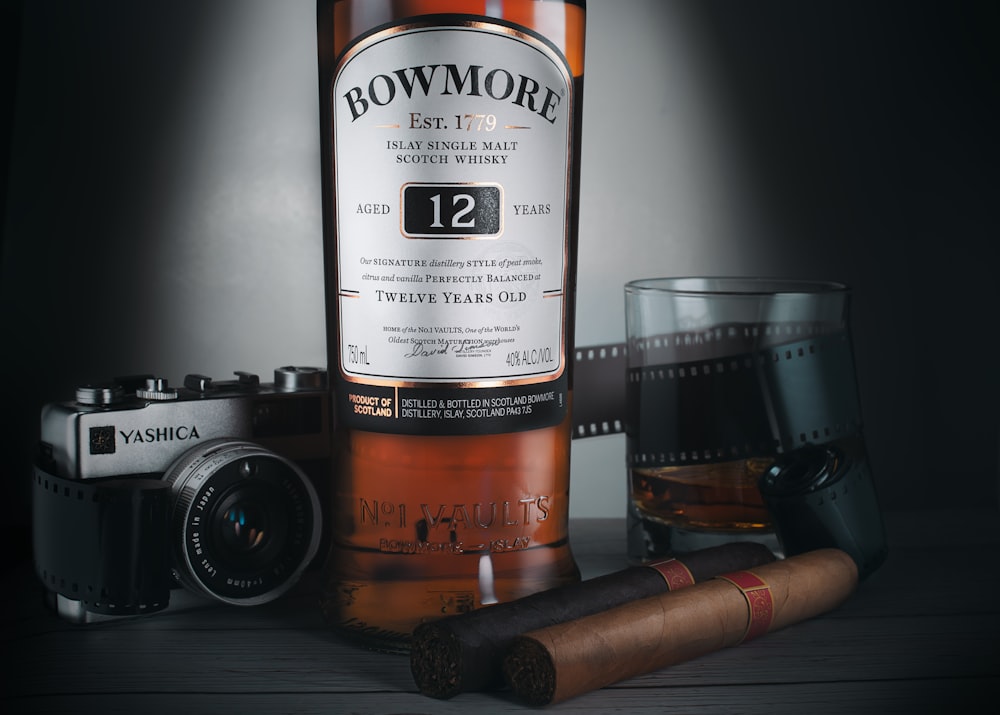 a bottle of whisky next to a camera and a glass