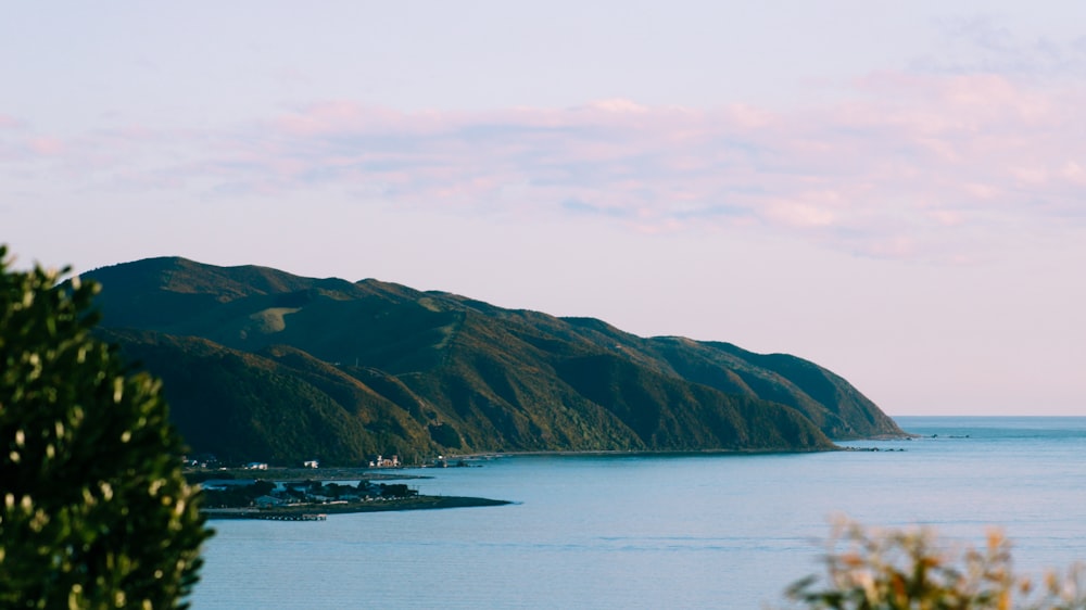 green and brown mountain beside body of water during daytime