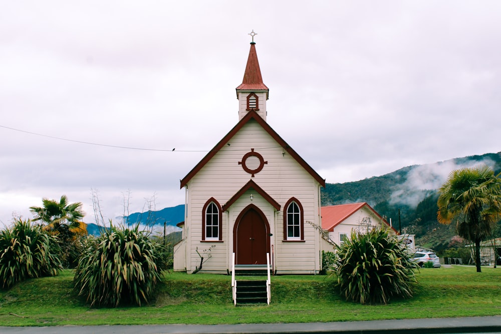 white and brown church near palm trees under white clouds during daytime