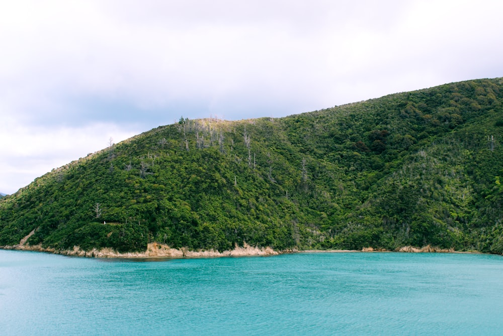 green mountain beside body of water during daytime