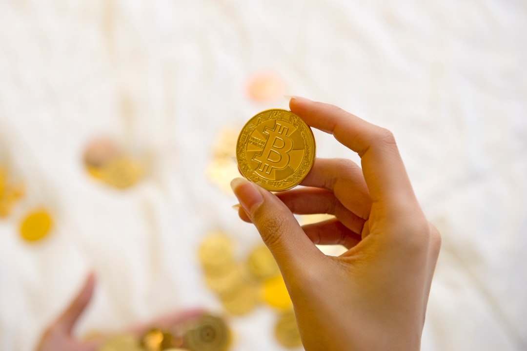 A hand holding a shining gold coin, symbolizing investment and value.