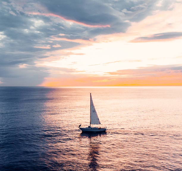 white sailboat on sea during sunset