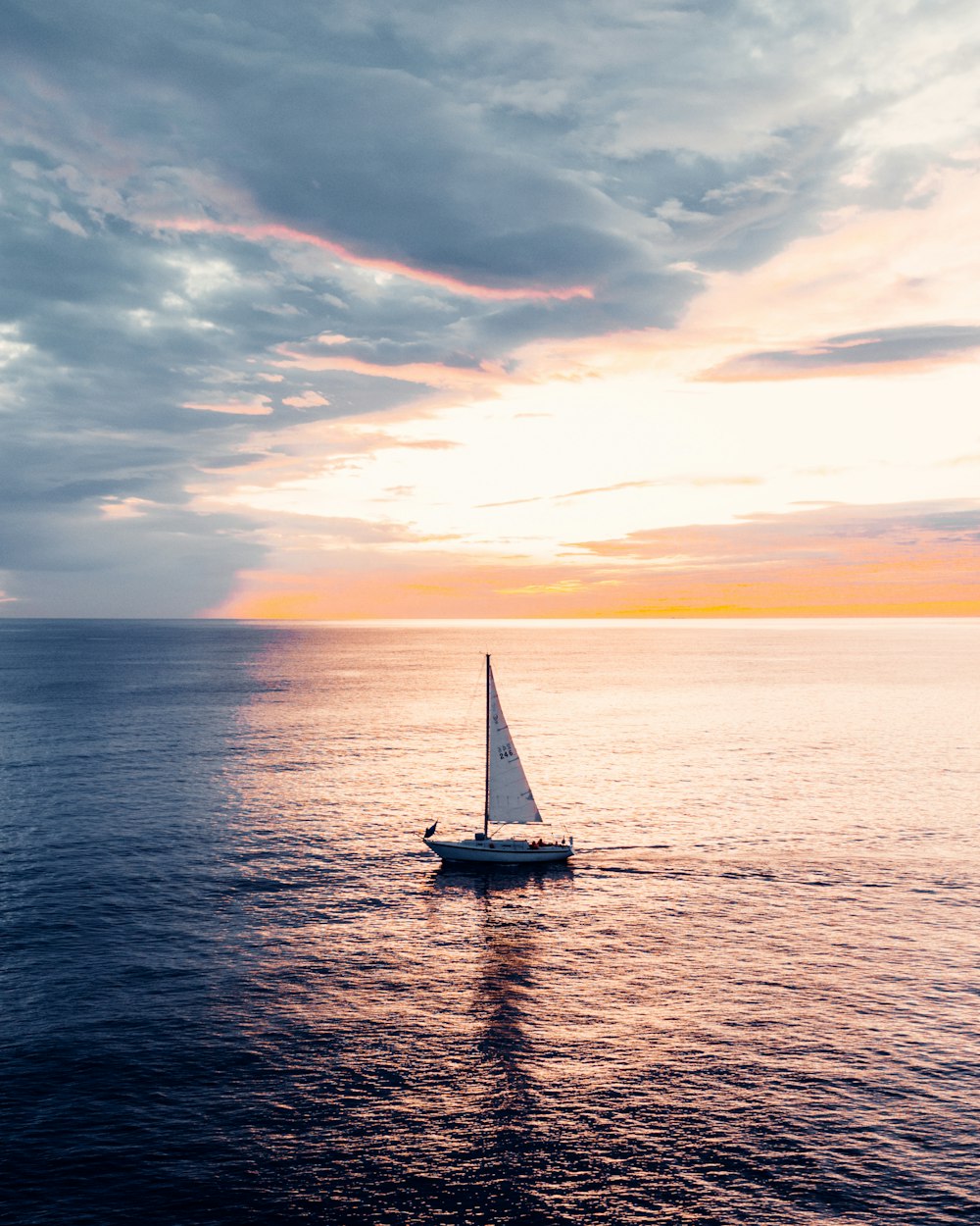 white sailboat on sea during sunset