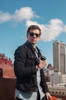A confident man posing with modern sunglasses against a city backdrop