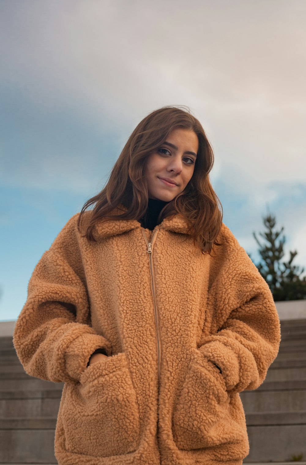 woman in brown coat standing on snow covered ground during daytime