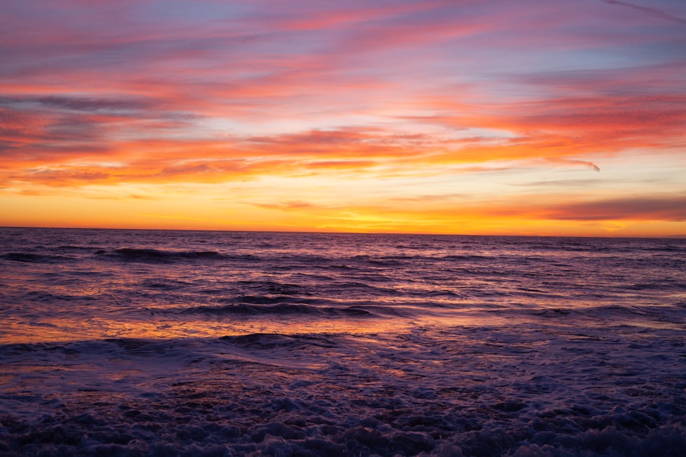 ocean waves crashing on shore during sunset