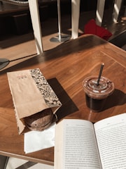 A close-up of a luxeloomed bag resting on a wooden table beside a cup of coffee, sunlight casting warm shadows.