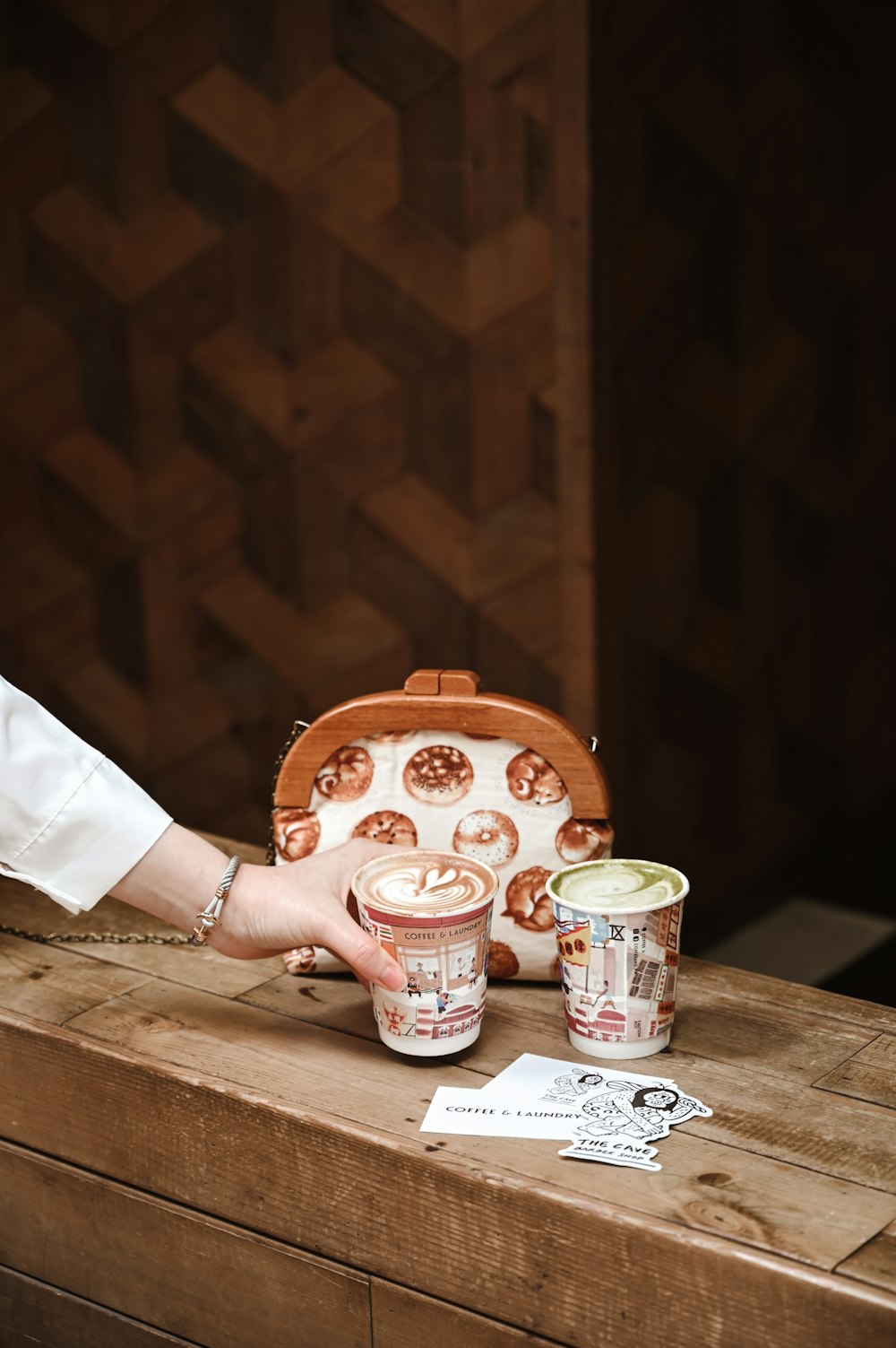 person holding white ceramic mug and white ceramic mug on brown wooden table