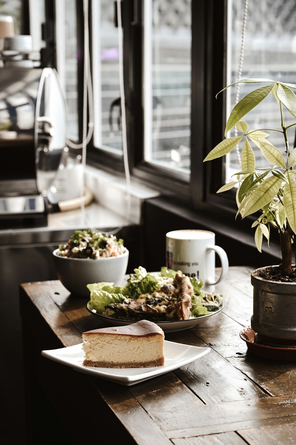 green plant on brown wooden chopping board beside white ceramic mug