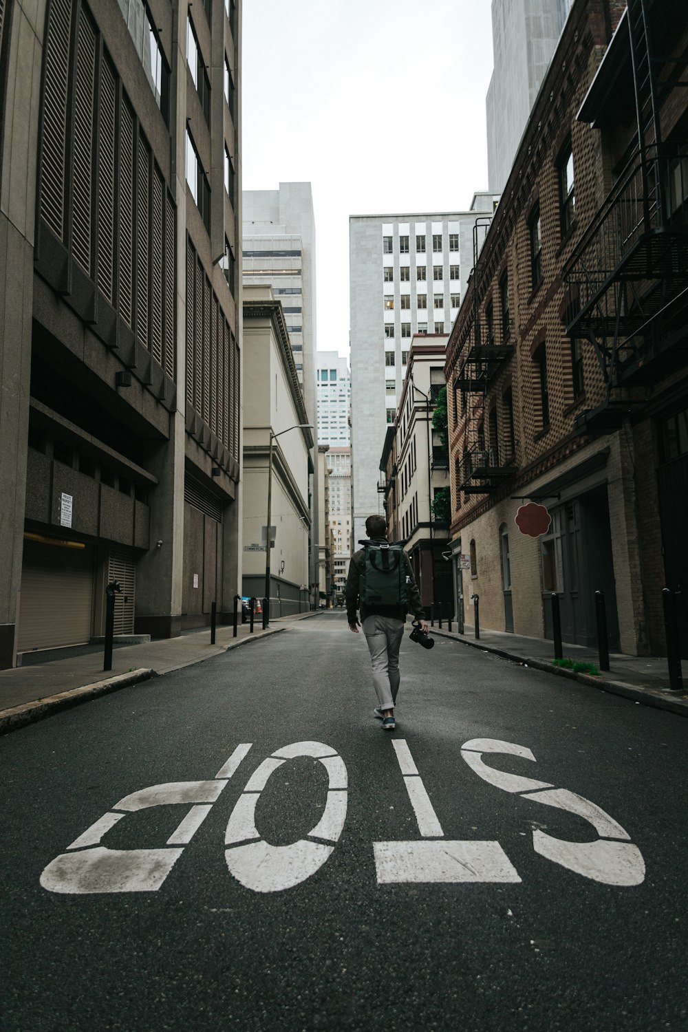 man in black jacket and black pants walking on pedestrian lane during daytime