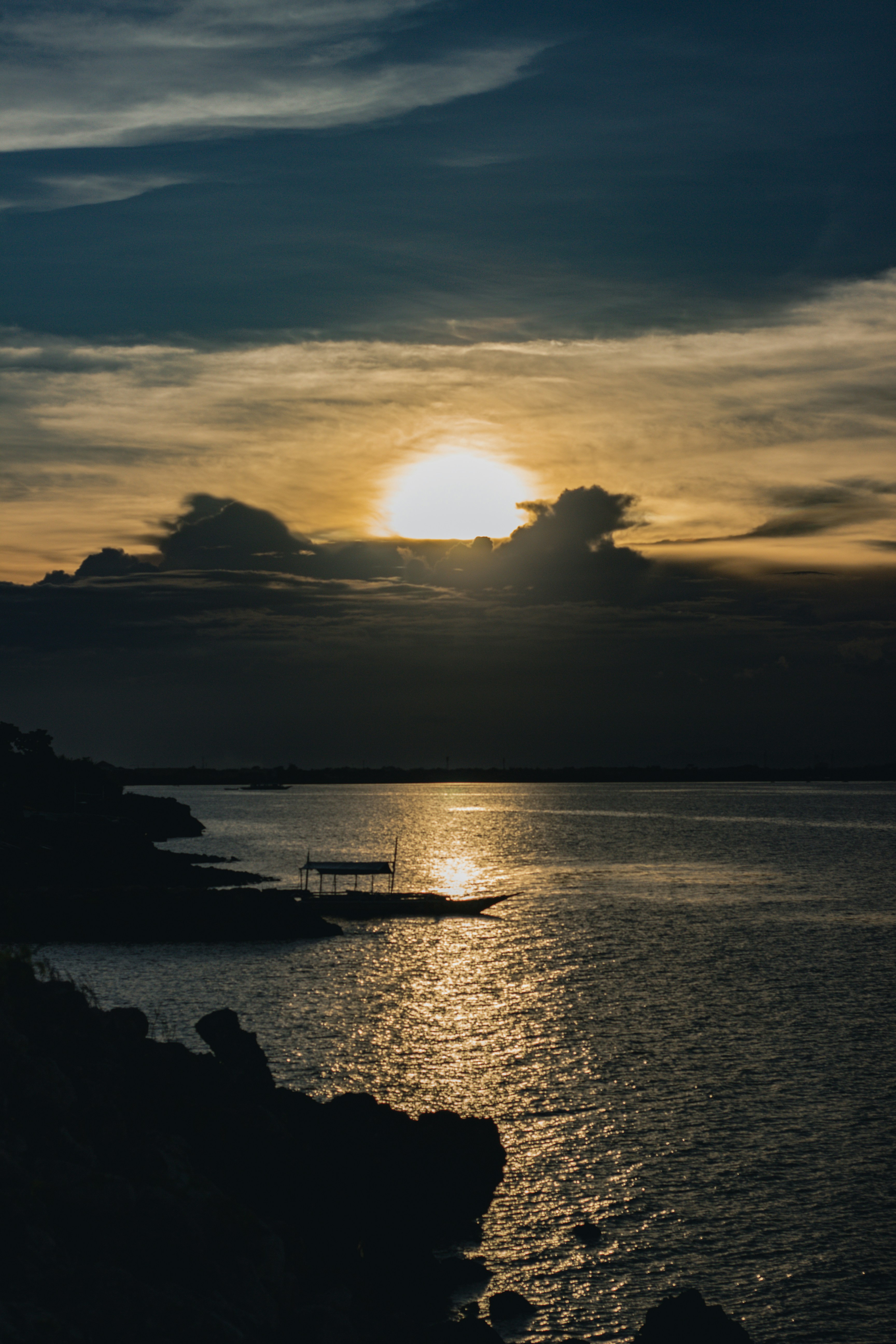 Sunset boat cruise on calm ocean water with golden sky and silhouetted passengers