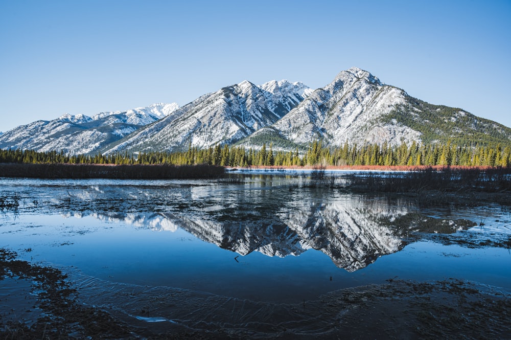 snow covered mountain near lake during daytime