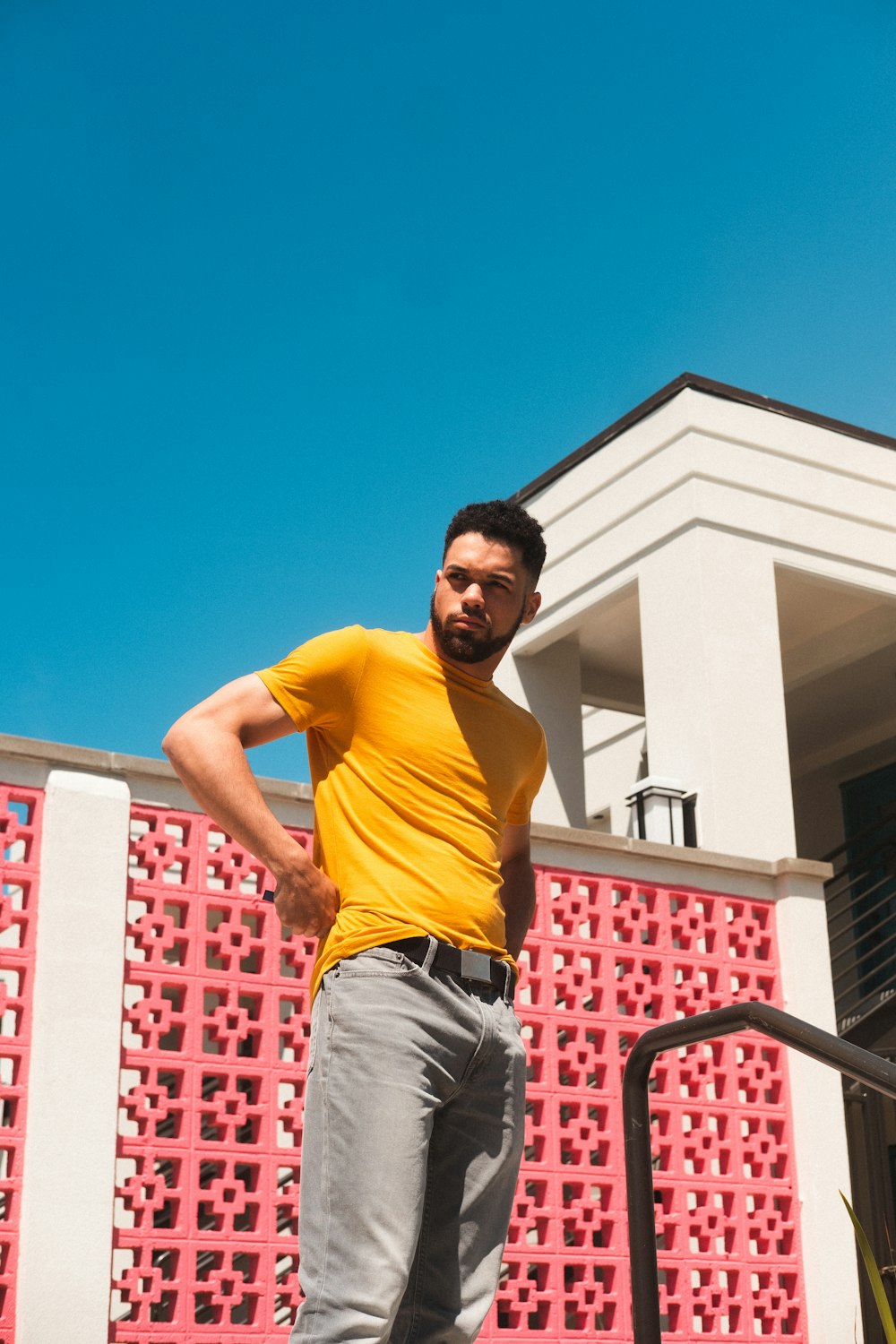 man in yellow crew neck t-shirt and black pants standing on black metal railings during