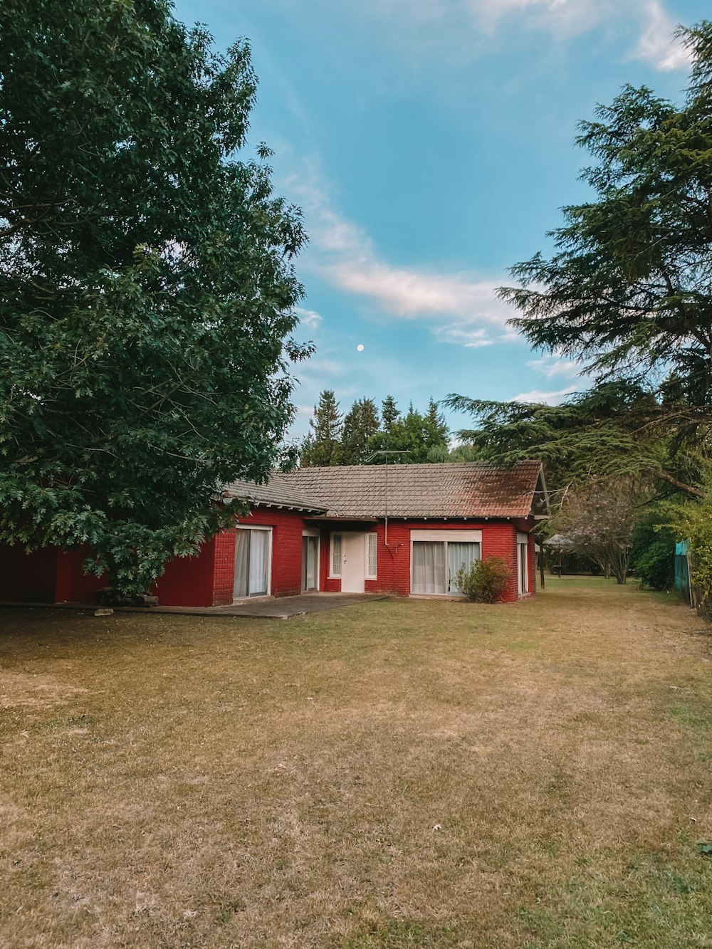 Maison en bois rouge et brun près des arbres verts sous le ciel bleu pendant la journée