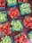 Brightly colored cartons filled with fresh strawberries and green grapes are arranged on a dark surface, creating a vibrant display. Each green carton is neatly packed with ripe, juicy strawberries or bunches of green grapes, showcasing a bountiful collection of fruit.