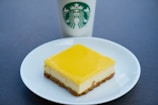 A tangy lemon cheesecake presented in a bright yellow box, showing the price clearly.
