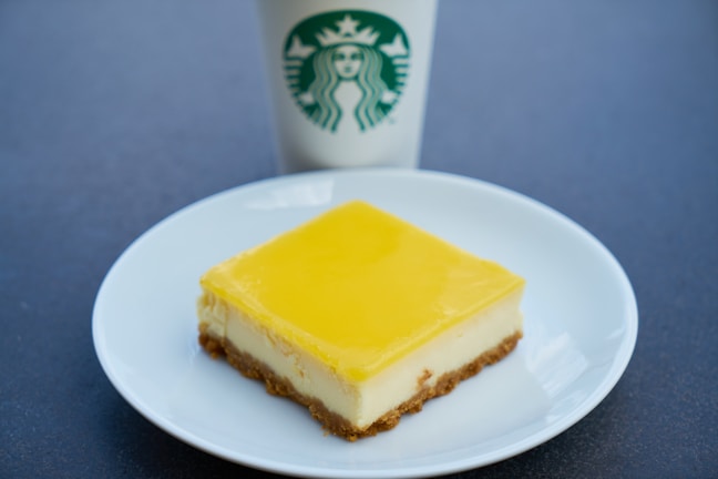 A close-up of a creamy lemon cheesecake garnished with lemon zest.