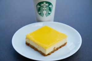 A tangy lemon cheesecake presented in a bright yellow box, showing the price clearly.