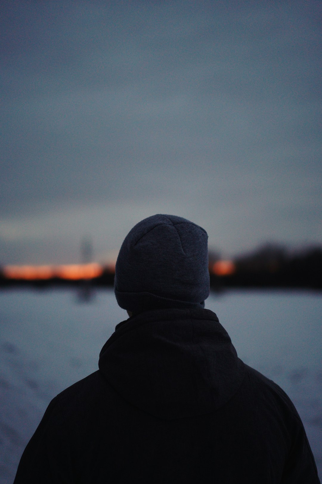 person in black hoodie standing near body of water during daytime