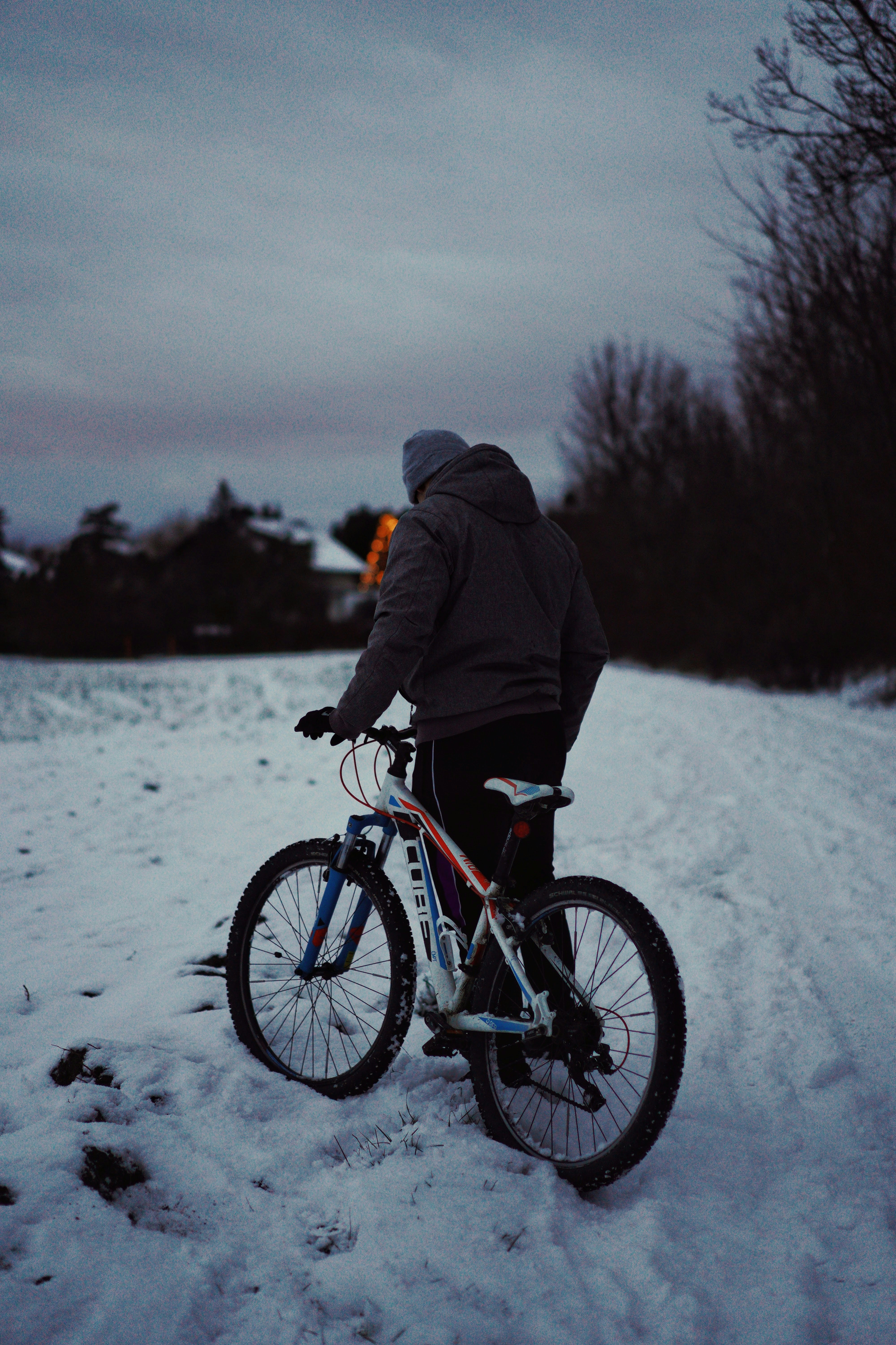 man in black jacket riding on black mountain bike on snow covered ground during daytime