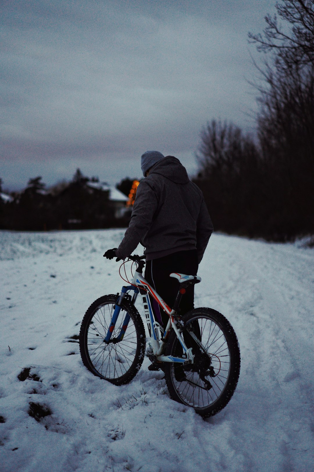 man in black jacket riding on black mountain bike on snow covered ground during daytime