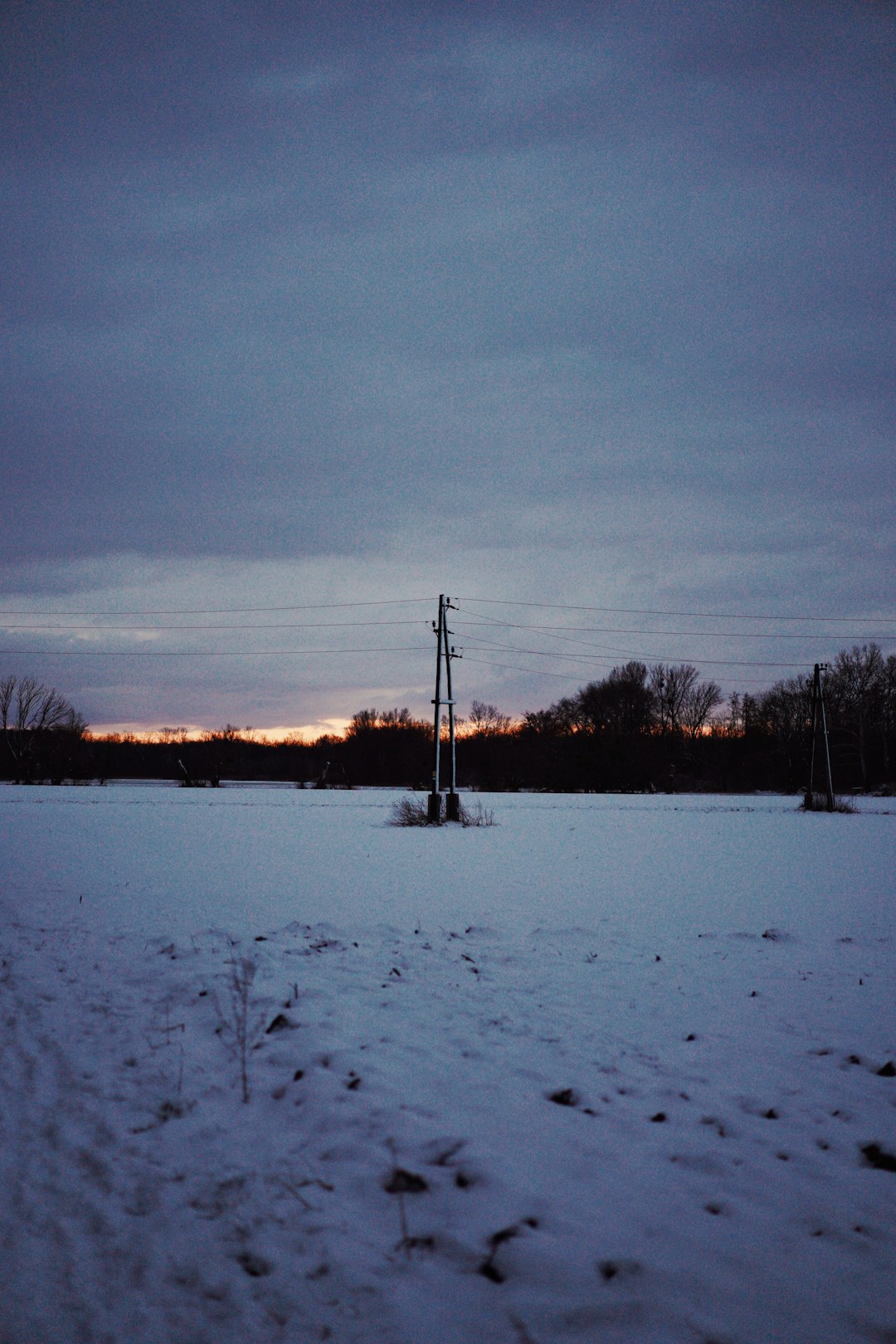 black electric post on snow covered ground during sunset