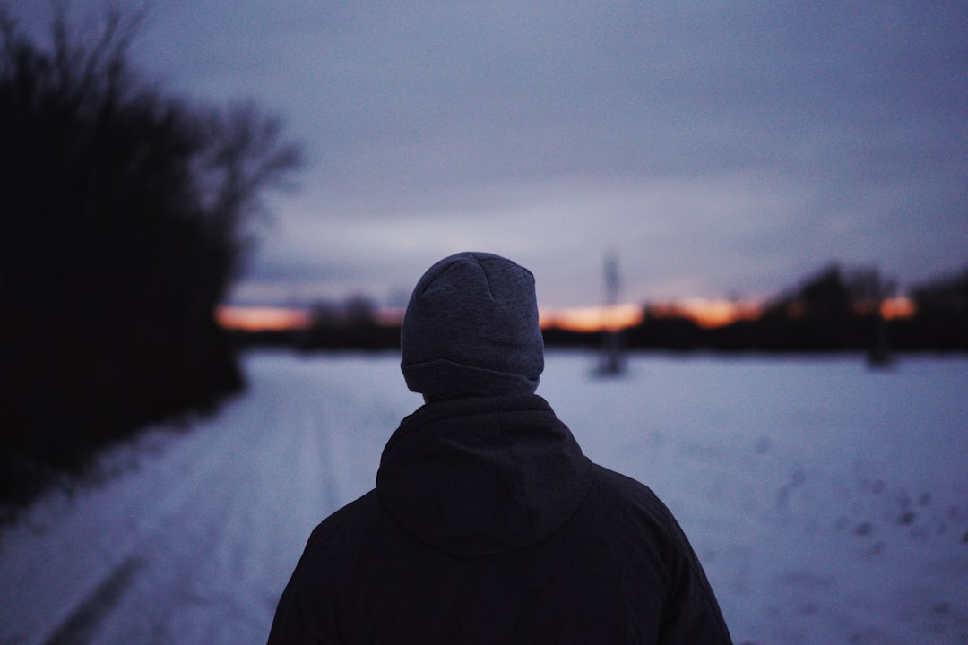 person in black hoodie standing near snow covered field during daytime
