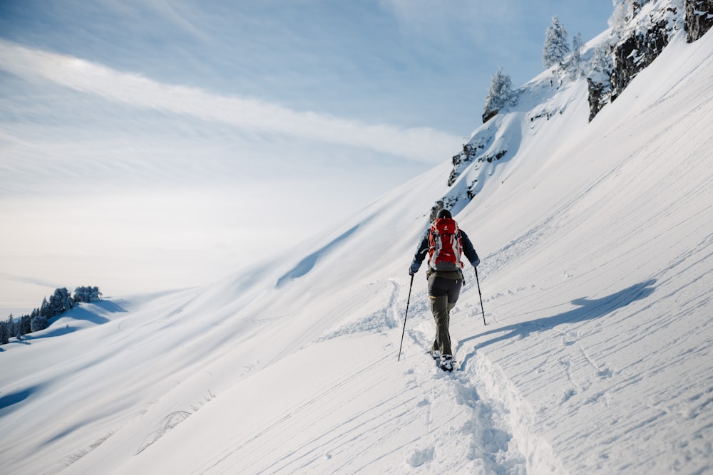 Eine Person, die auf Skiern einen verschneiten Hügel hinaufgeht